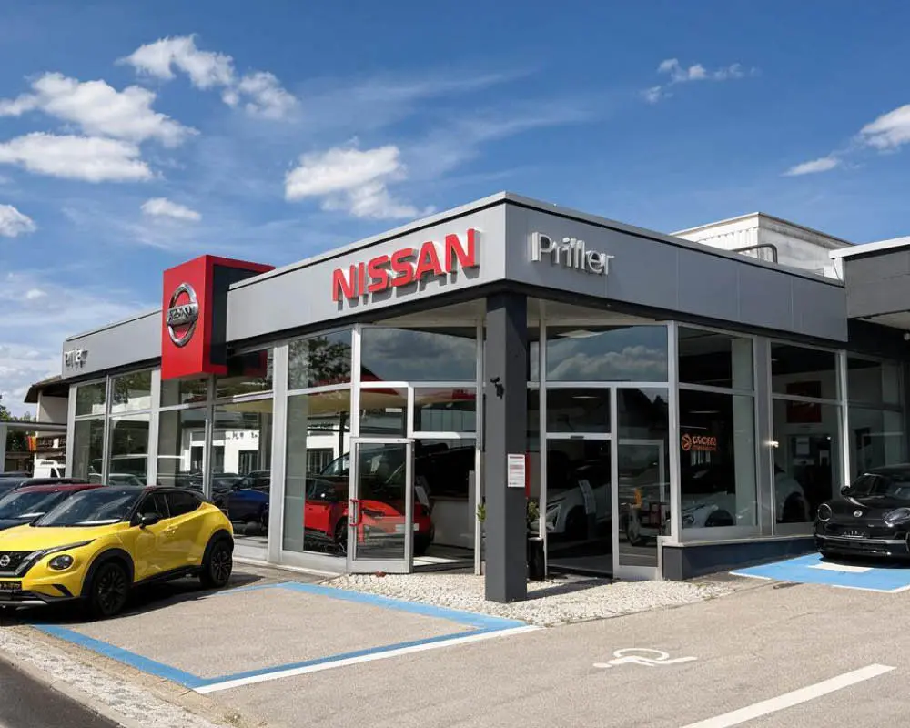 Autohaus Priller bei abendlicher Dämmerung. Vor dem Autohaus stehen 2 Fahrzeuge
