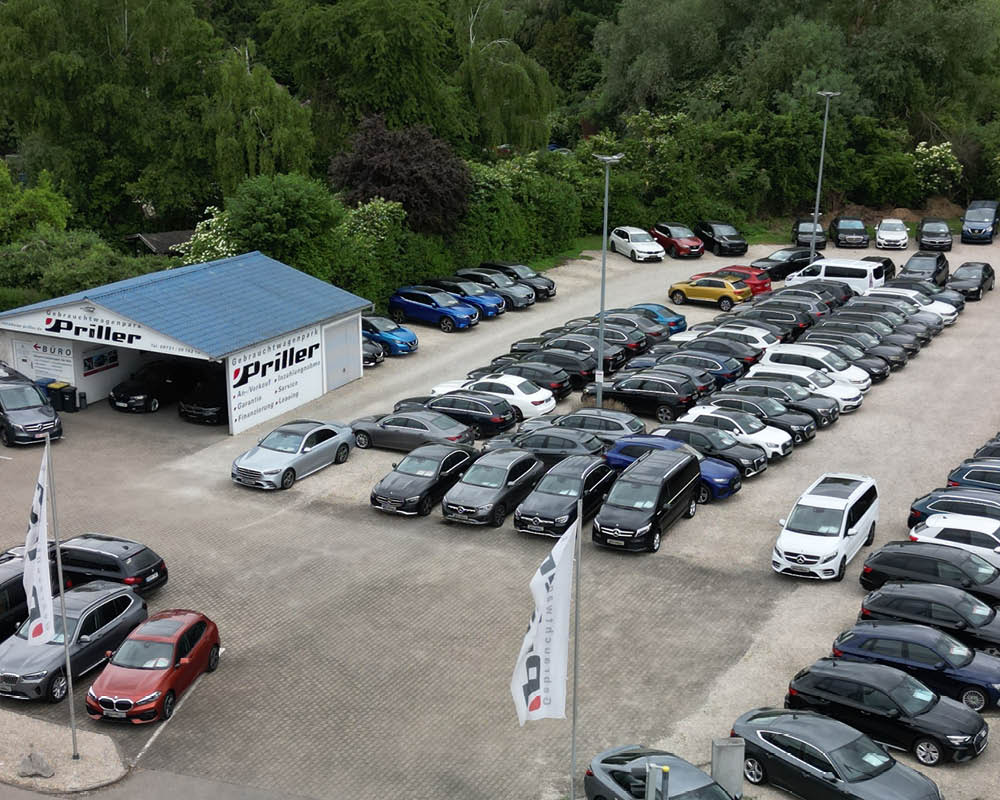 Der Gebrauchtwagenpark von Autohaus Priller aus der Vogelperspektive. Eine Vielzahl an Fahrzeugen stehen auf dem Hof